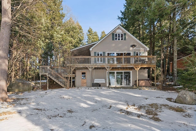 snow covered back of property with a wooden deck and a jacuzzi