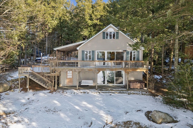 rear view of house with a hot tub and a deck