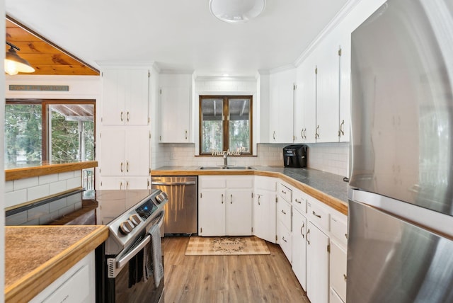 kitchen featuring appliances with stainless steel finishes, tasteful backsplash, white cabinetry, sink, and light wood-type flooring