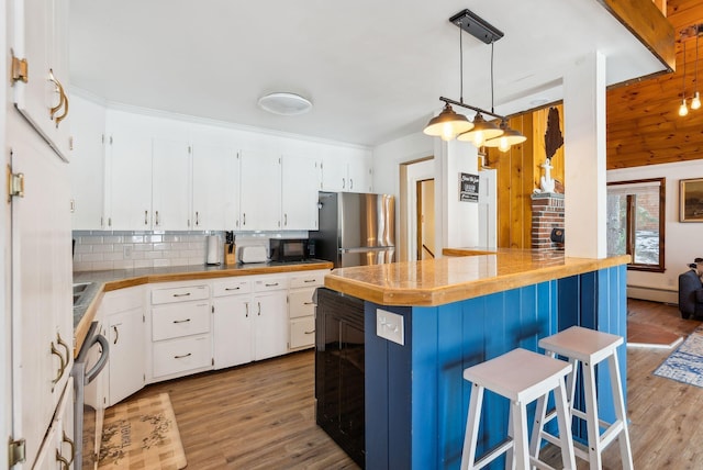 kitchen featuring pendant lighting, white cabinetry, a kitchen breakfast bar, and stainless steel refrigerator