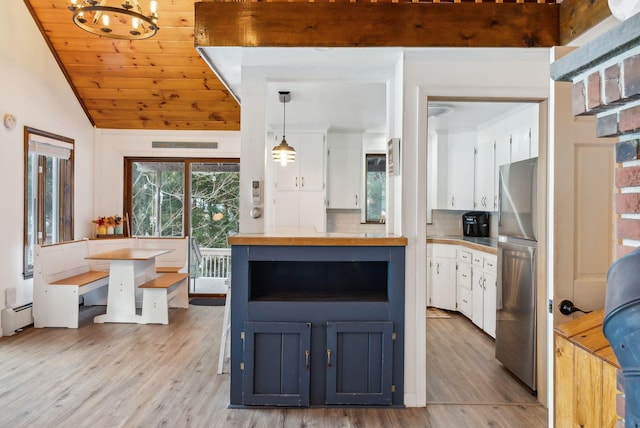 kitchen featuring a baseboard radiator, pendant lighting, white cabinets, and stainless steel refrigerator