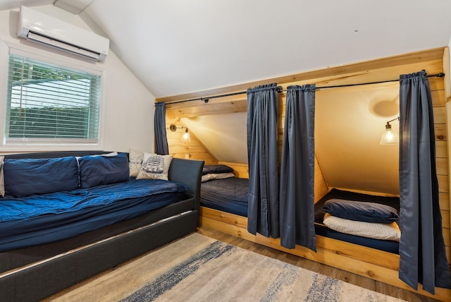 bedroom featuring hardwood / wood-style flooring, an AC wall unit, and lofted ceiling