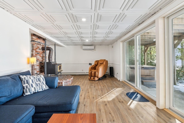 living room featuring a baseboard radiator, an AC wall unit, a wood stove, and light wood-type flooring