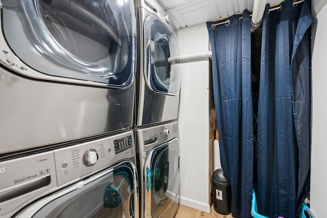 laundry room featuring stacked washer / drying machine and light hardwood / wood-style flooring