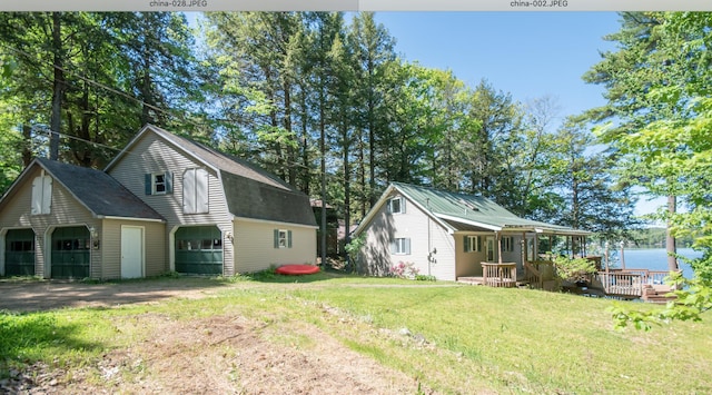 view of property exterior featuring a garage, an outdoor structure, a deck, and a lawn