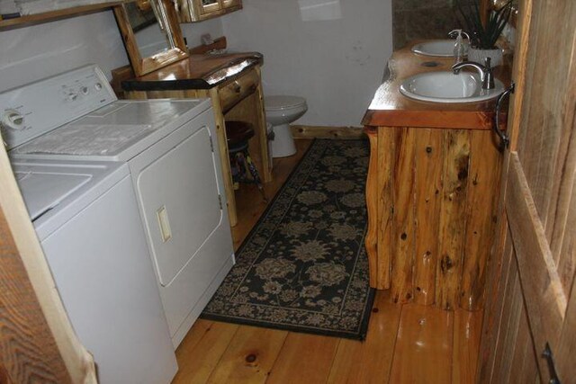 laundry area featuring light wood-type flooring, separate washer and dryer, and sink