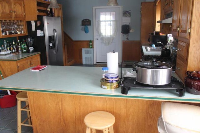 kitchen featuring a breakfast bar, sink, stainless steel fridge with ice dispenser, and kitchen peninsula