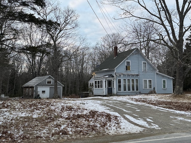 view of front of home featuring an outbuilding, a chimney, and a sunroom