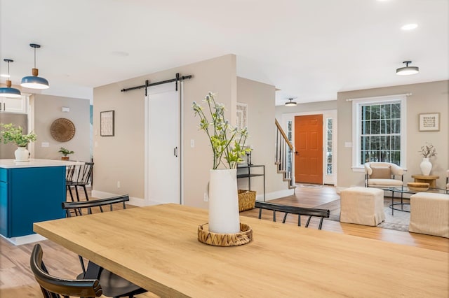 dining area featuring a barn door and light hardwood / wood-style floors