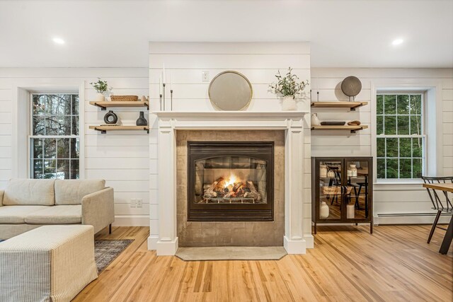 sitting room featuring a baseboard radiator, hardwood / wood-style floors, a tile fireplace, and a wealth of natural light