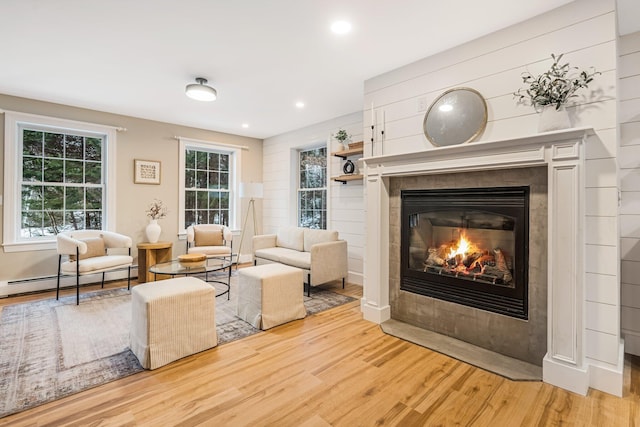 sitting room with hardwood / wood-style floors, a tile fireplace, and a baseboard heating unit