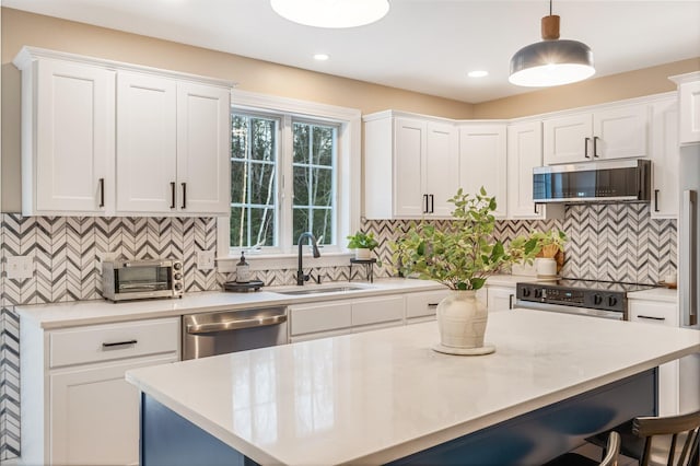 kitchen with sink, white cabinetry, hanging light fixtures, and stainless steel appliances