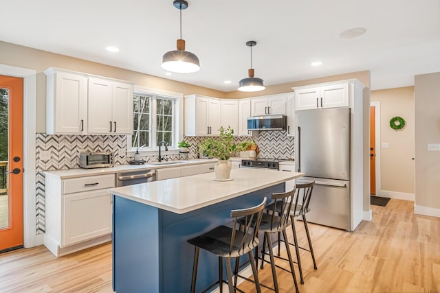 kitchen featuring pendant lighting, white cabinets, and stainless steel appliances