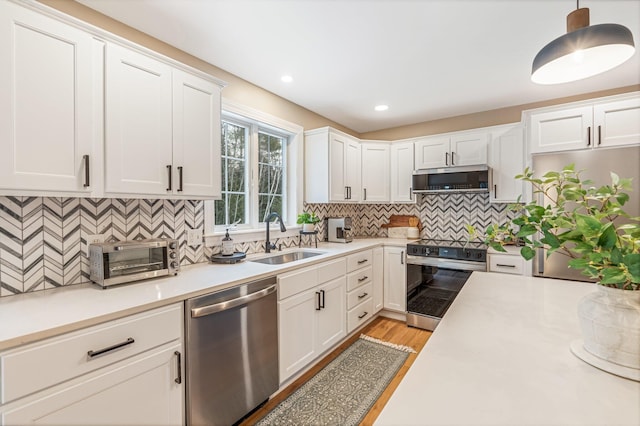 kitchen with sink, white cabinets, pendant lighting, and stainless steel appliances