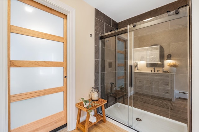 bathroom with hardwood / wood-style floors, baseboard heating, and an enclosed shower