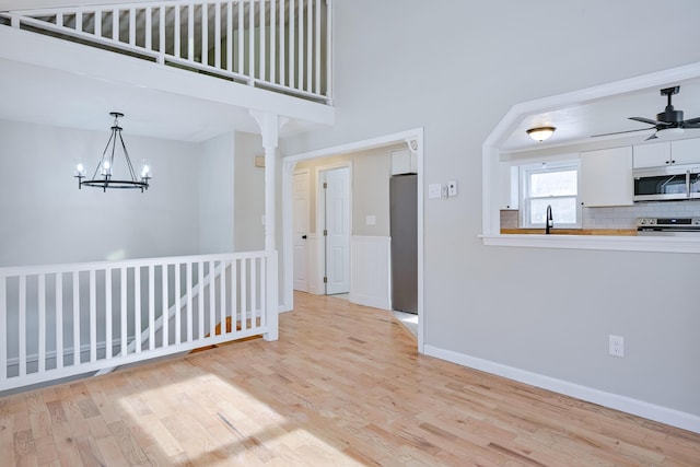 interior space featuring sink, ceiling fan with notable chandelier, and light hardwood / wood-style flooring