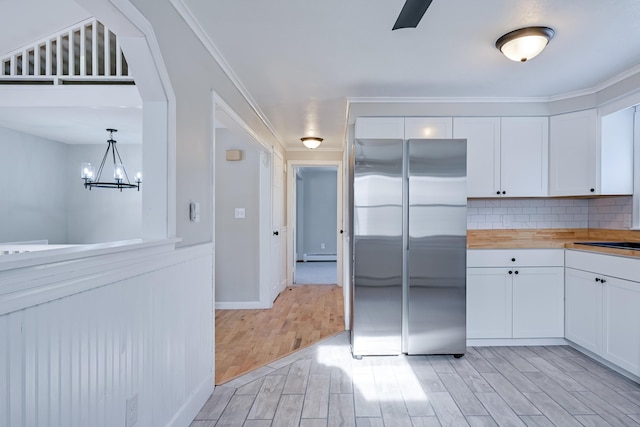 kitchen featuring wood counters, stainless steel refrigerator, white cabinetry, a baseboard radiator, and hanging light fixtures