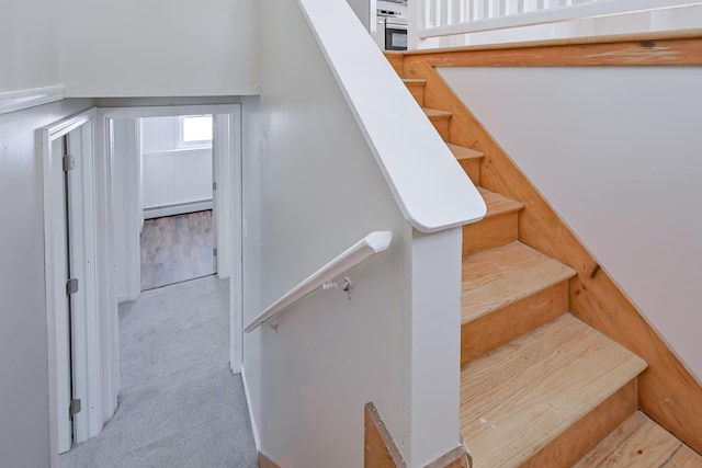 stairway with carpet floors and a baseboard heating unit