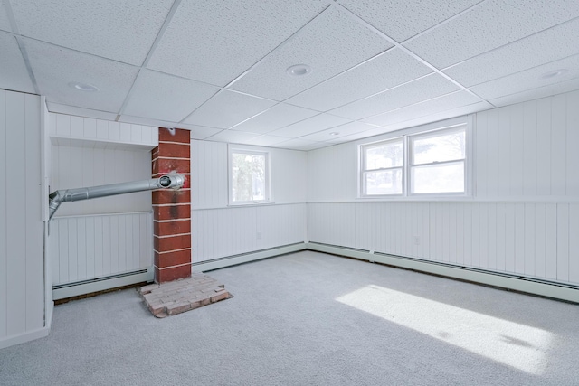 basement with a drop ceiling, a baseboard heating unit, and light colored carpet