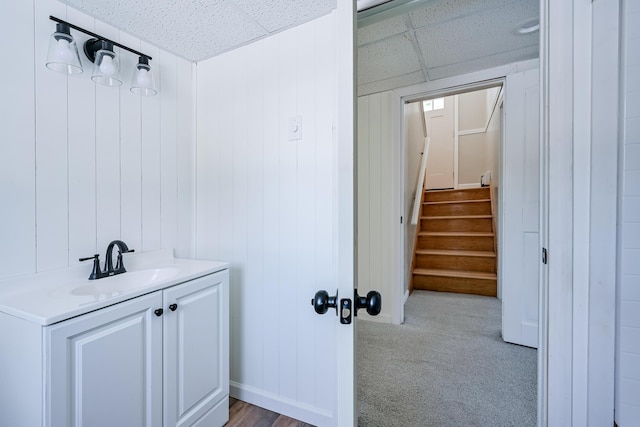 bathroom featuring vanity, a paneled ceiling, and wooden walls