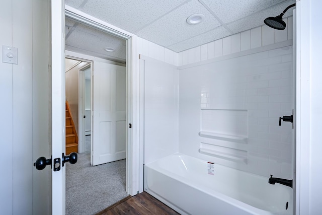 bathroom with a drop ceiling, hardwood / wood-style flooring, and  shower combination