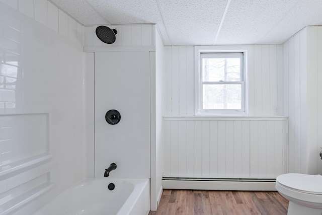 bathroom with a baseboard radiator, tub / shower combination, wood-type flooring, and a paneled ceiling