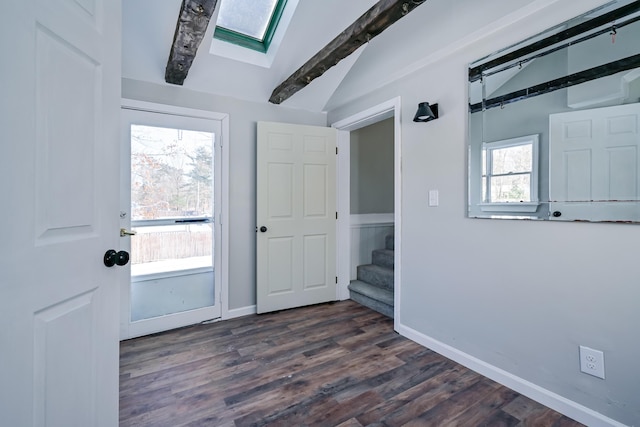 foyer entrance with dark wood-type flooring and vaulted ceiling with skylight