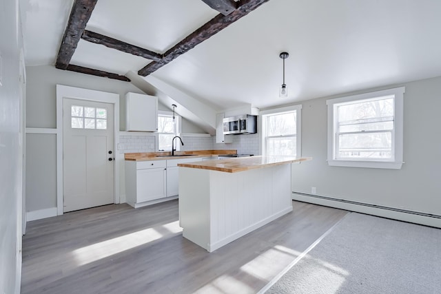 kitchen with pendant lighting, sink, white cabinets, wood counters, and decorative backsplash