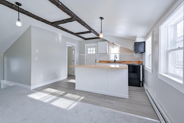 kitchen featuring pendant lighting, butcher block countertops, sink, baseboard heating, and tasteful backsplash