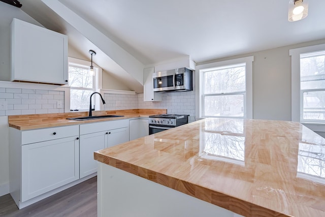 kitchen featuring sink, wooden counters, white cabinets, stainless steel appliances, and backsplash