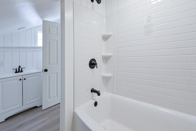 bathroom featuring hardwood / wood-style flooring, vaulted ceiling, sink, and washtub / shower combination