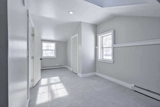 unfurnished bedroom with vaulted ceiling, multiple windows, and a baseboard heating unit