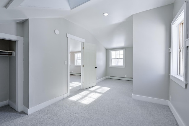 unfurnished bedroom featuring baseboard heating, a closet, vaulted ceiling, and light carpet