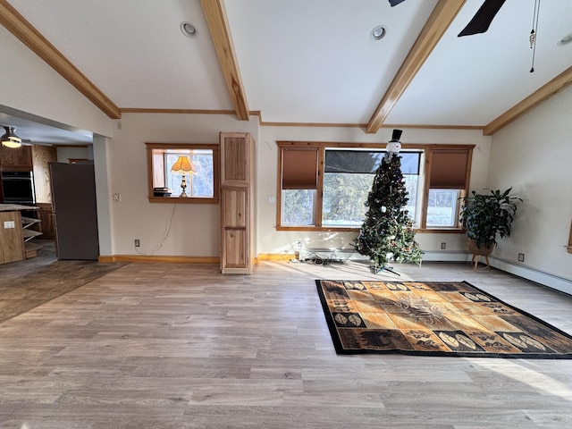 unfurnished living room featuring baseboards, a ceiling fan, ornamental molding, wood finished floors, and vaulted ceiling with beams