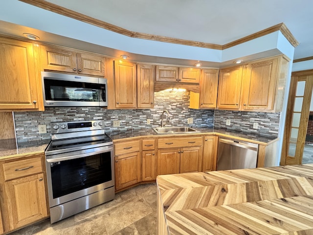 kitchen with appliances with stainless steel finishes, decorative backsplash, a sink, and ornamental molding