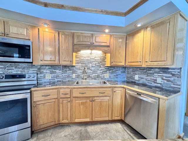 kitchen featuring crown molding, stainless steel appliances, tile counters, backsplash, and a sink