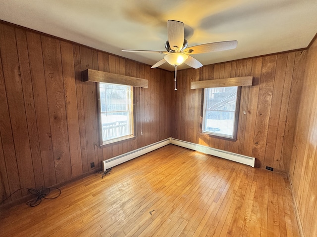 spare room with light wood-style floors, a baseboard radiator, plenty of natural light, and a ceiling fan