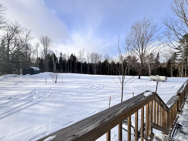 yard covered in snow featuring a wooded view