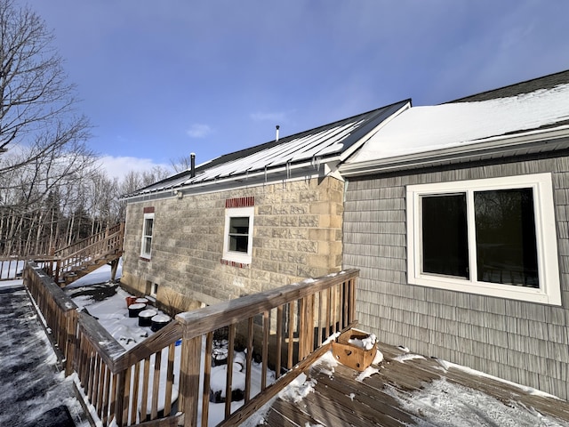 snow covered property featuring metal roof and a wooden deck