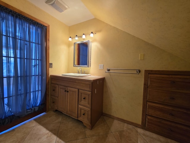 bathroom featuring vaulted ceiling, baseboards, vanity, and tile patterned floors