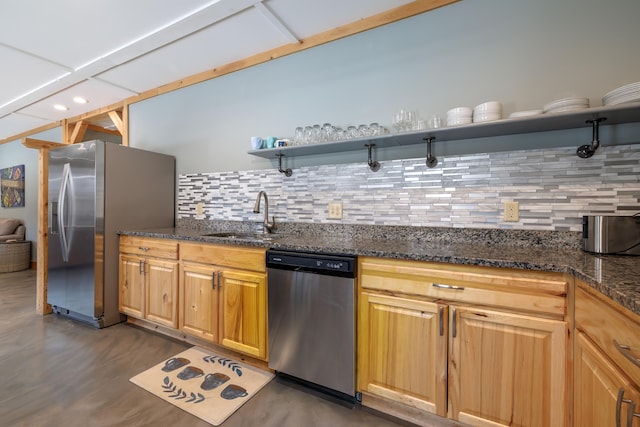 kitchen with appliances with stainless steel finishes, sink, backsplash, and dark stone counters