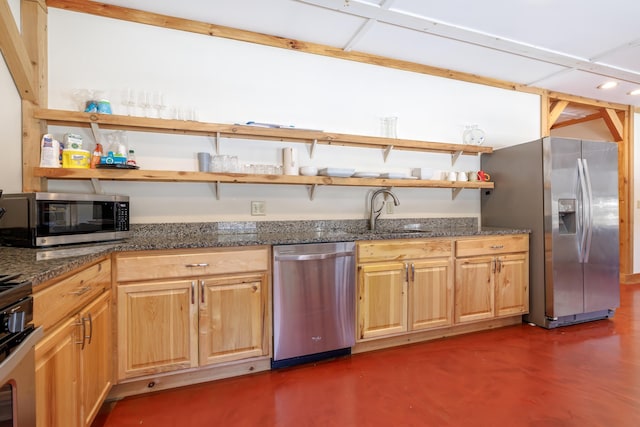 kitchen with appliances with stainless steel finishes, sink, light brown cabinets, and dark stone counters