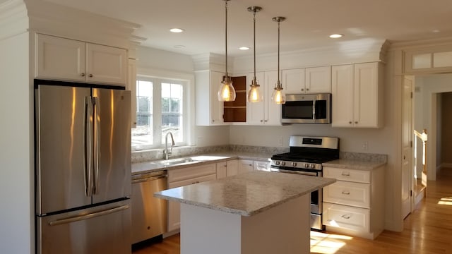 kitchen with a kitchen island, decorative light fixtures, white cabinetry, sink, and stainless steel appliances