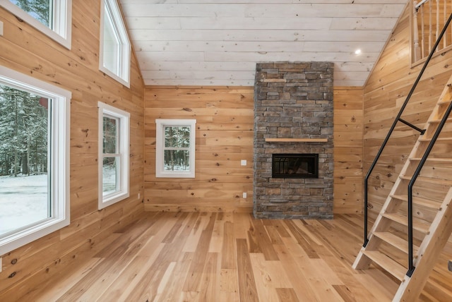 unfurnished living room with hardwood / wood-style flooring, vaulted ceiling, wooden ceiling, and wooden walls