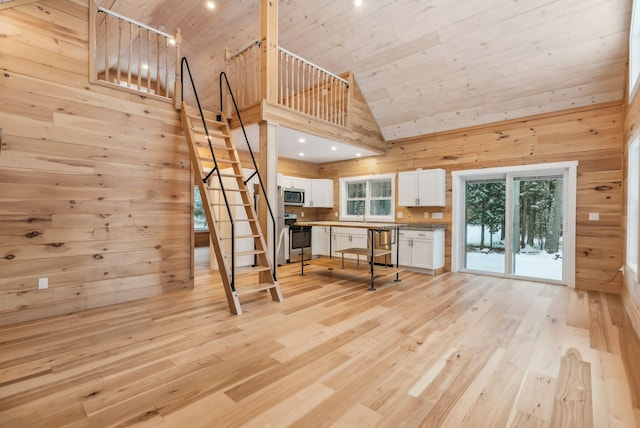 unfurnished living room featuring high vaulted ceiling, light hardwood / wood-style flooring, wooden ceiling, and wood walls