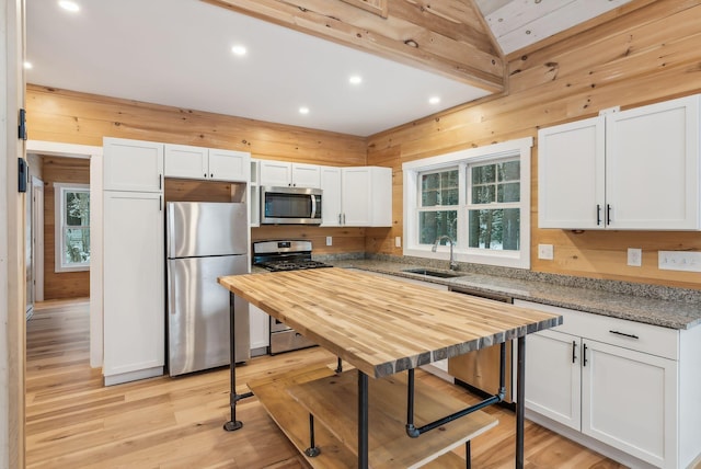 kitchen with white cabinetry, stainless steel appliances, sink, and dark stone counters