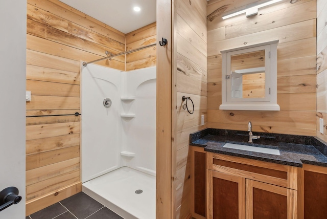 bathroom with a shower, vanity, tile patterned floors, and wood walls