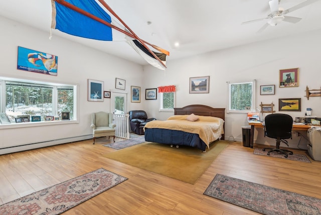 bedroom with hardwood / wood-style flooring, ceiling fan, and baseboard heating