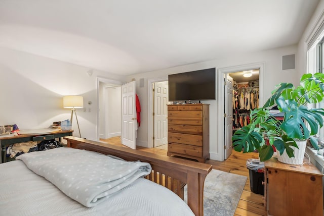 bedroom featuring a spacious closet, light hardwood / wood-style floors, and a closet