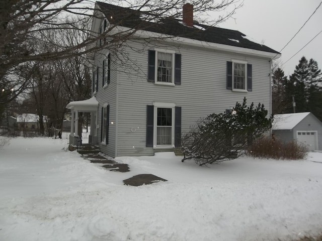 exterior space with a chimney, a detached garage, and an outdoor structure